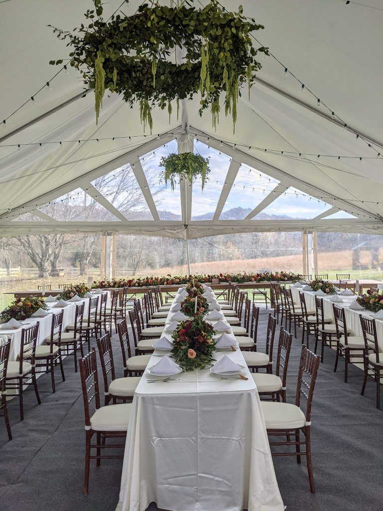 Inside a wedding venue tent. Tables decorated in white and flowers