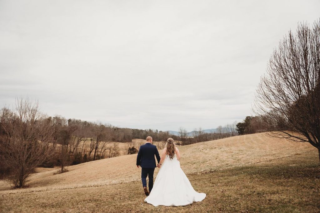 Bride and groom walking into a field in the winter