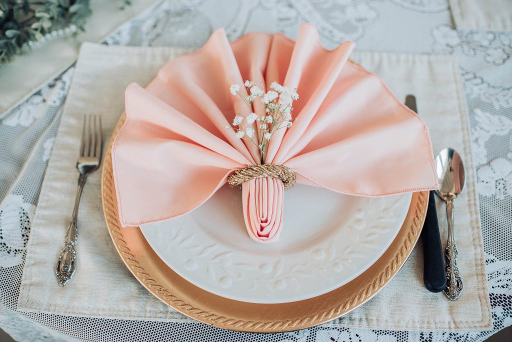 plate setting, pink napkin fanned out on plate with baby's-breath