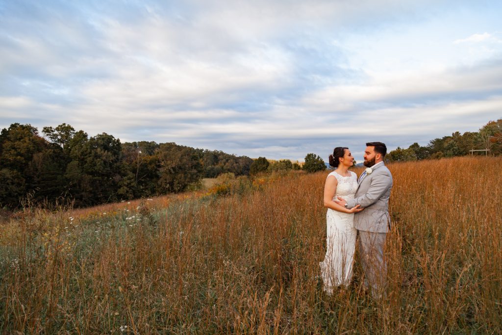 a bride and groom standing in a feild.