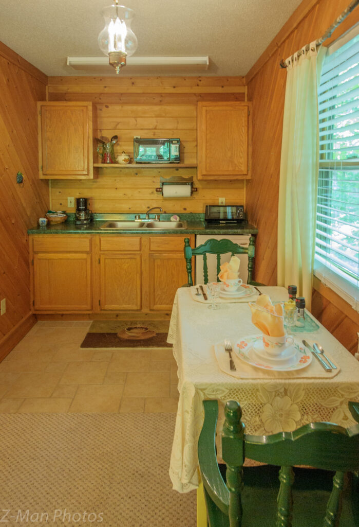 A small kitchen with wooden cabinets and a dining area with a table set for two.
