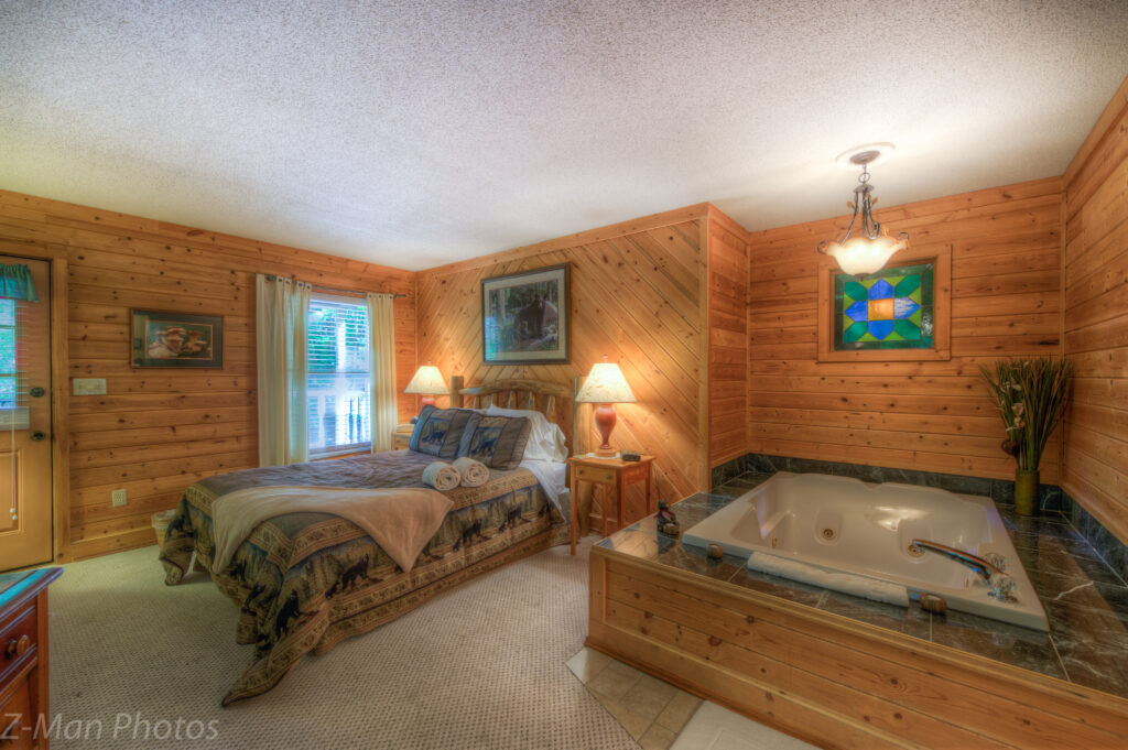 A wide-angle view of a room with a bed, a jacuzzi, and wood paneling