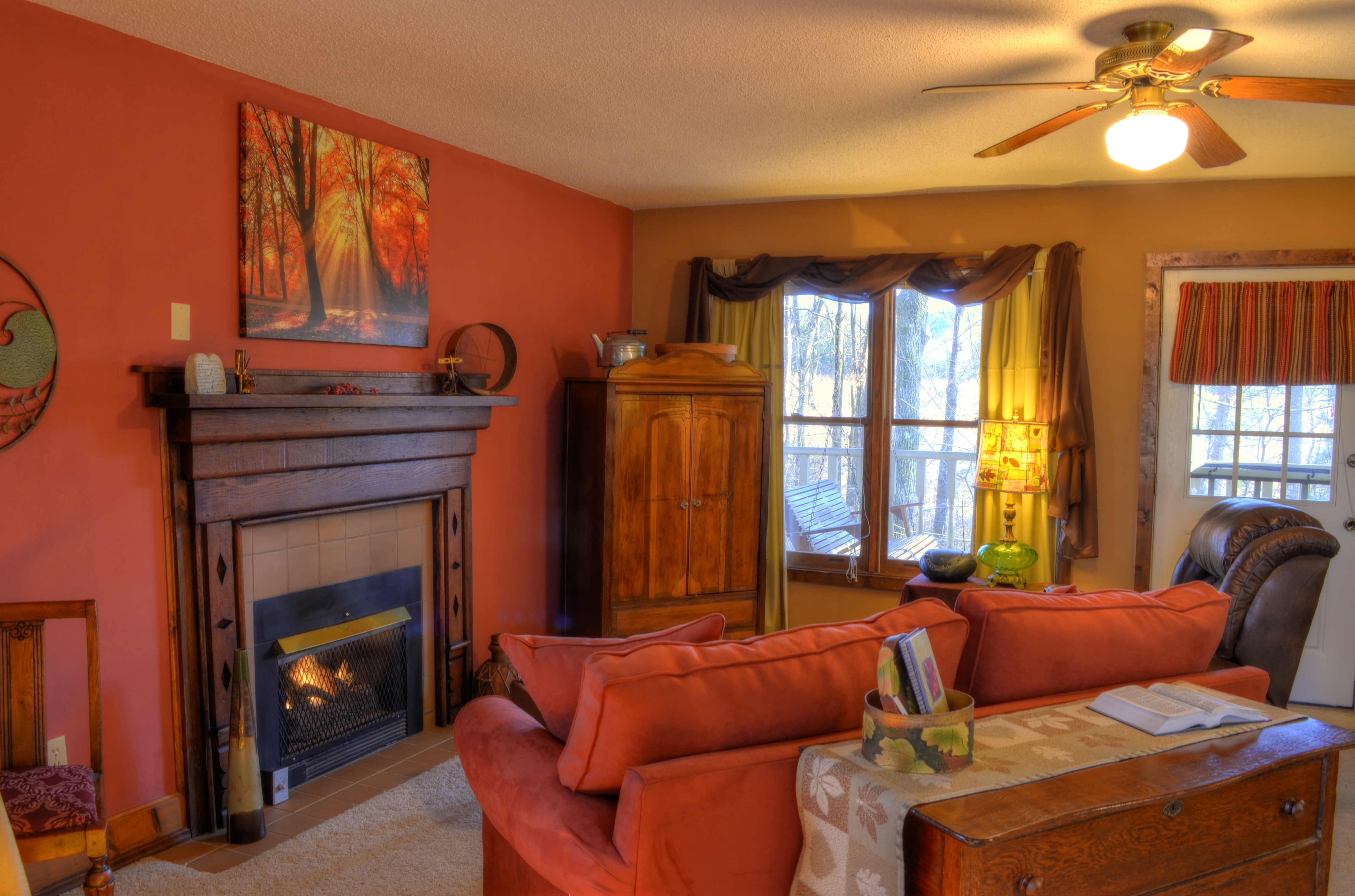 A cozy living room with a fireplace, sofa, coffee table, and windows.