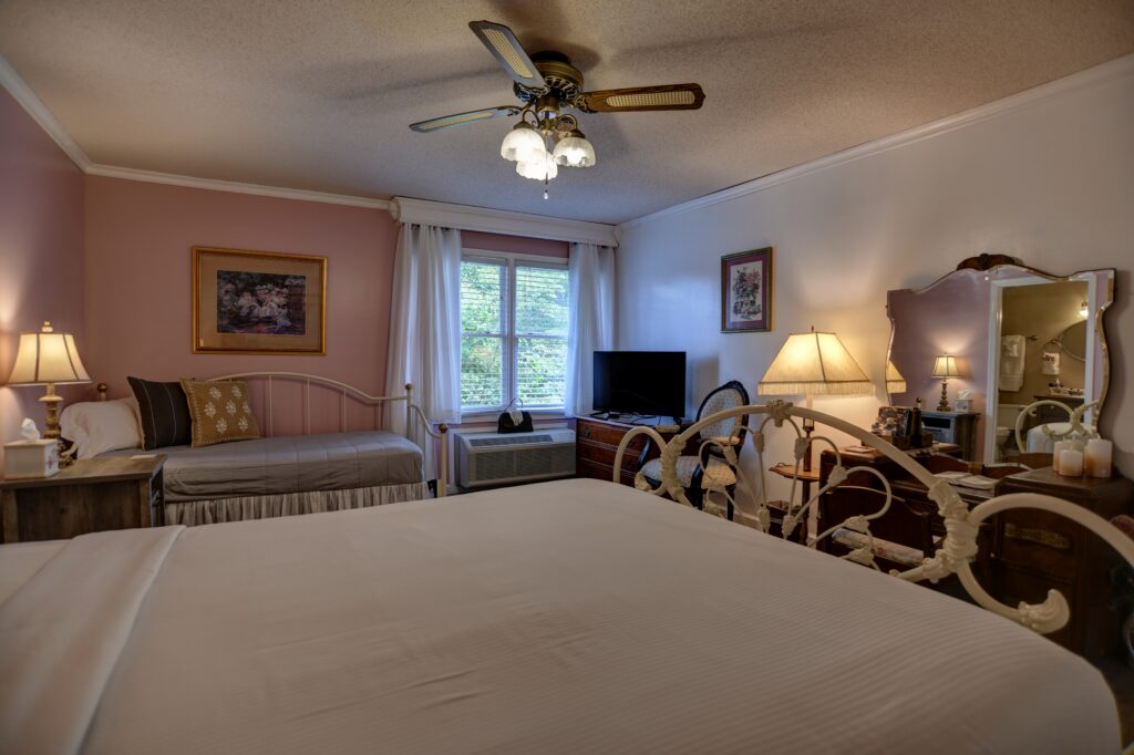 A wide view of a hotel room with two beds, a TV, and a window