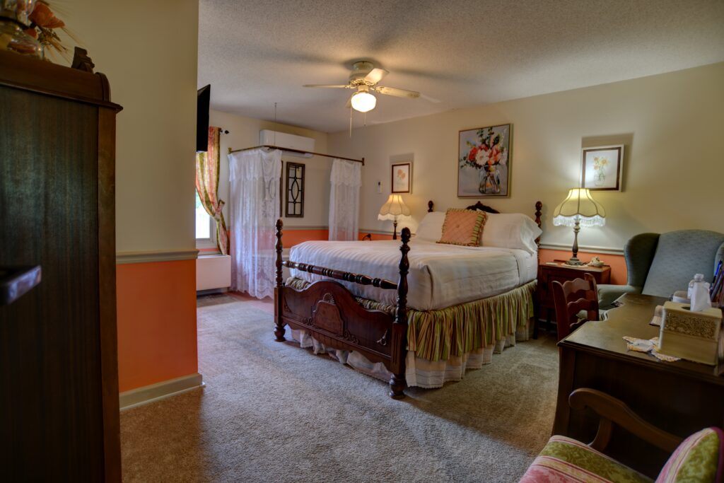A wide view of a hotel room with a bed, desk, chair, and lamp