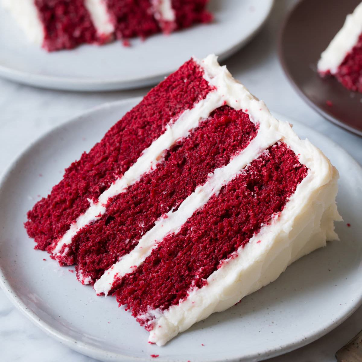 a slice of red velvet cake with white frosting on a plate