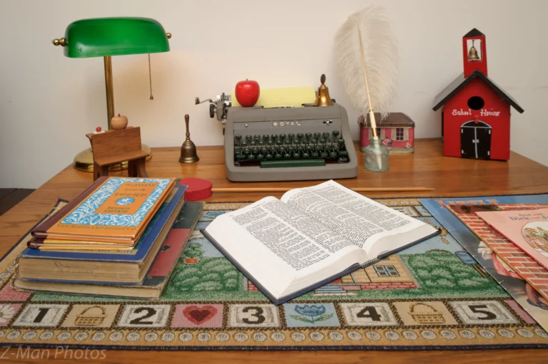 A wooden desk with a typewriter, books, and a green lamp.