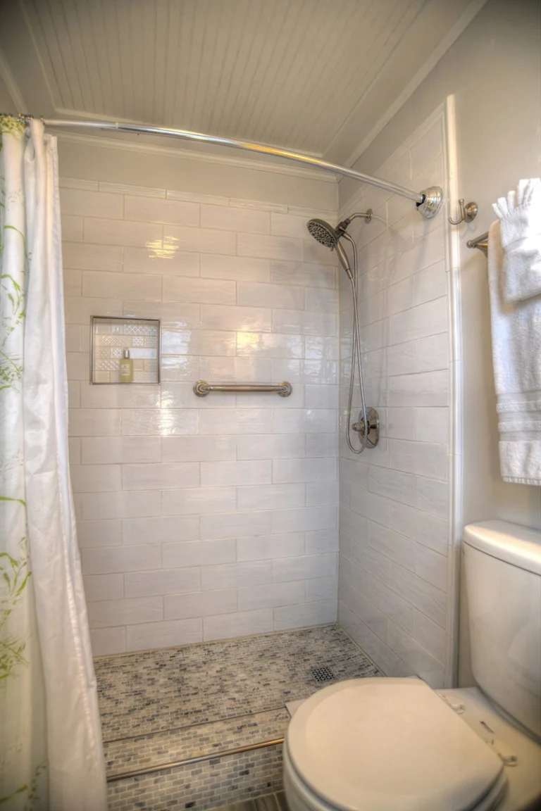 A clean bathroom with a shower, toilet, and white tiles