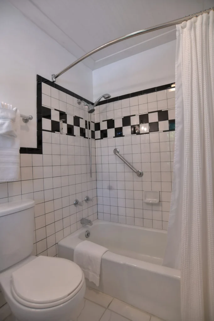 A bathroom with a toilet, bathtub, and shower with white and black tiles.